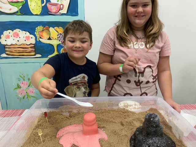 Дети строят вулкан из песка на мастерской